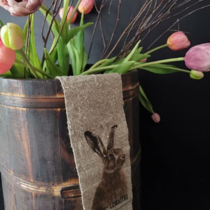 Linnen lint haas aan een oude houten pot met kunsttulpen