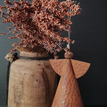 Roestige metalen engel met een Nepalese pot en kunstplanten