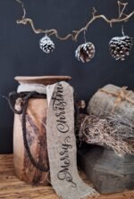 Shabby kerst lint met tekst Merry Christmas om een Nepalese pot, gecombineerd met een houten poer, tijmkrans en dennenappels
