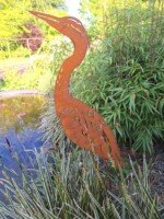 Roestige metalen reiger bij de vijver