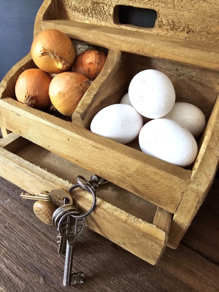 Bruin houten gruttersbakje met lade voor sleutels, gevuld met ui en ei