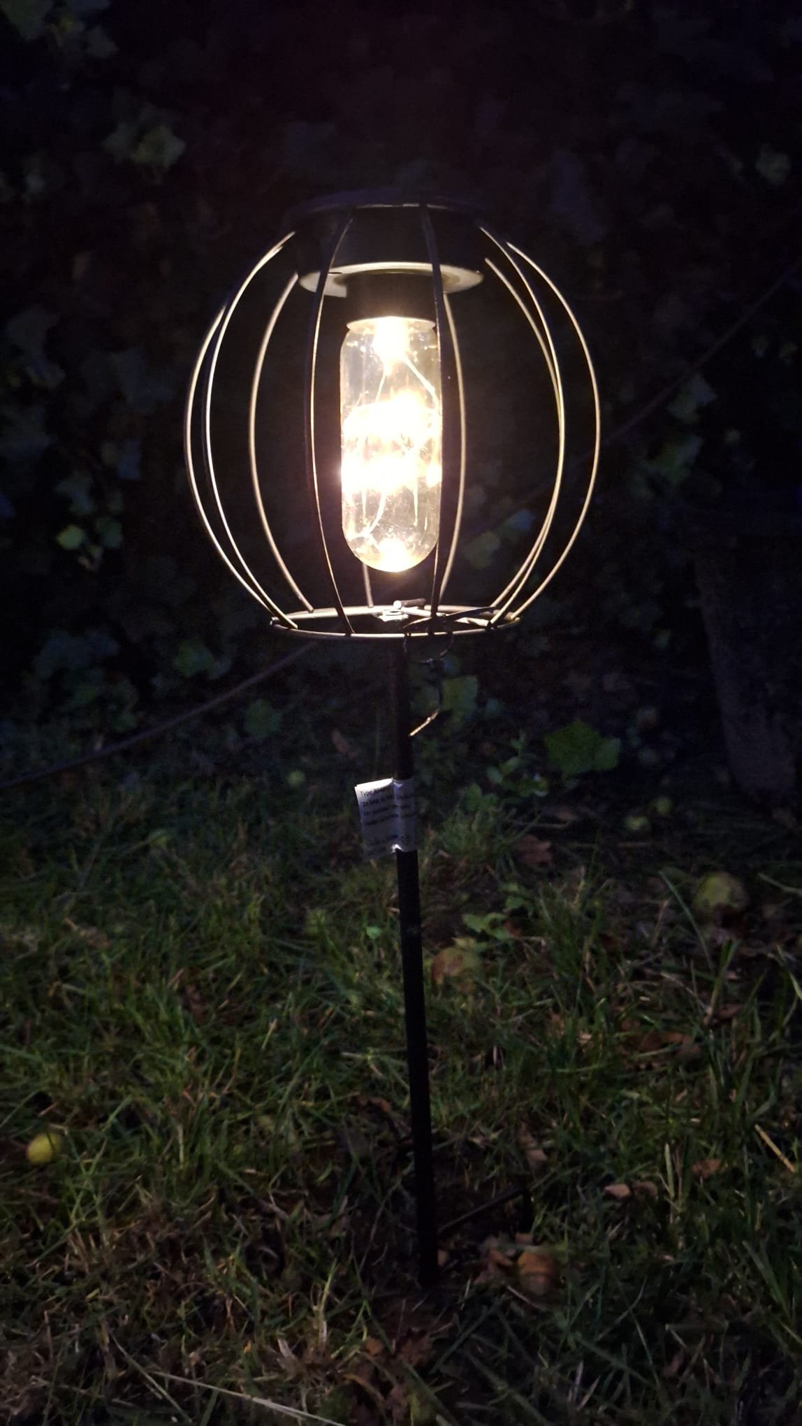 solar-tuinlamp-op-prikstok-met-glazen-pot-landelijke-sfeerverlichting 1 Solar tuinlamp met metalen kooi en glazen pot – brandend in de avond