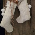 Kerstsok Ellabritt S crème gevuld met cadeau en dennentak aan een oude houten deur