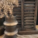 Klein metalen louvre luik op standaard in sober interieur