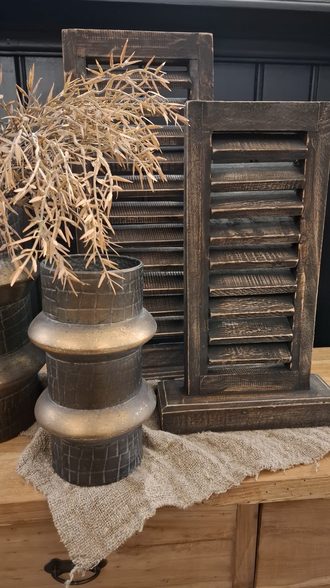 vintage-grijs-louvre-luik-40 1 Klein metalen louvre luik op standaard in sober interieur