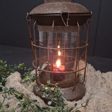 Windlicht stormlamp op een linnen shabby doekje afgestyled met een groene kunsttak.