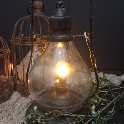 Zwart metalen LED lamp op een shabby doek en roestige vogelkooien op de achtergrond .