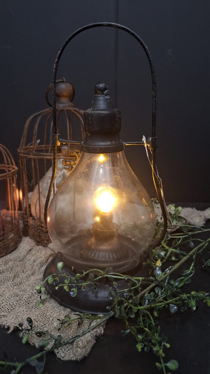 Zwart metalen LED lamp op een shabby doek en roestige vogelkooien op de achtergrond .