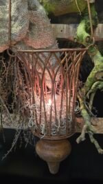 Roestige theelicht hanger gevuld met tillandsia en led kaars voor sfeer. gehangen aan een decoratie trap.