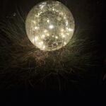 Glazen lichtbol met warm LED-licht in tuin bij nacht