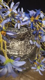 Landelijke zwarte kruik met paarse kunstbloemen