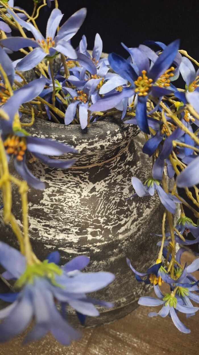 Landelijke zwarte kruik met paarse kunstbloemen