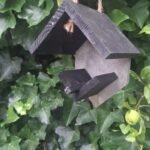 Zwart houten pindakaashuisje voor vogels in landelijke stijl voor tuin of balkon