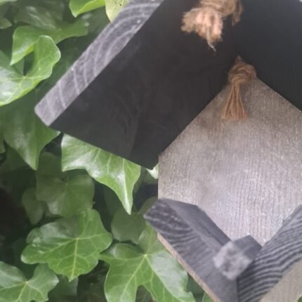 Zwart houten pindakaashuisje voor vogels in landelijke stijl voor tuin of balkon
