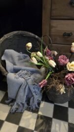 Grijze Woonplaid in basket met kunsttulpen en kievietsbloemen.