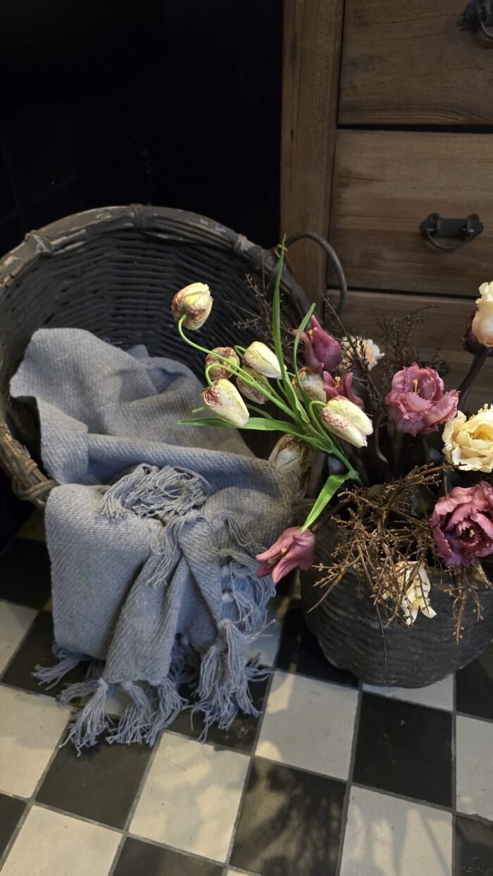 Grijze Woonplaid in basket met kunsttulpen en kievietsbloemen.
