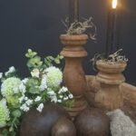 Houten ballen met teak houten kandelaars op een shabby doek en gedecoreerd met een kunstbloemenboeket