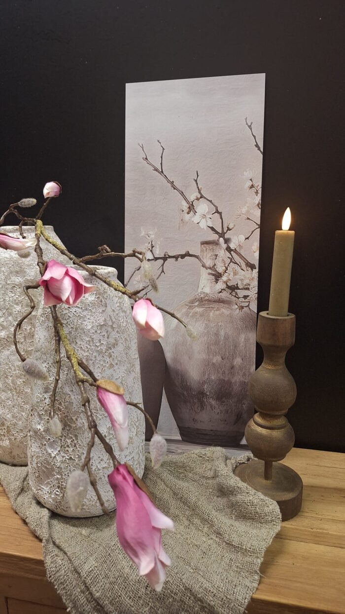 Landelijk wandbord met afbeelding van kruik en magnolia tak, decoratief met witte vaas en houten kandelaar met kaars, sfeervolle landelijke woondecoratie.