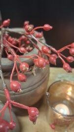 Kunst tak met rode besjes in vaas op houten tafel